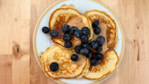 pancakes z borówkami i masłem orzechowym na talerzu